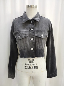Dettaglio della giacca di jeans nera lavata vintage con bottoni metallici e orlo a frange
