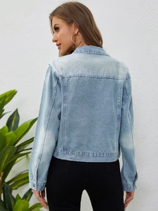 Detail of light blue washed denim jacket featuring classic back seam and buttoned cuffs