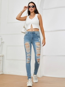 Detail of light blue skinny jeans featuring distressed ripped knees and frayed edge finish