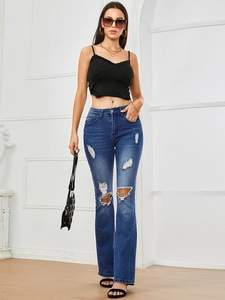 Full body view of women's ripped flare jeans styled with a black lace camisole and heels