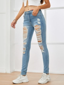 Detail view of light blue distressed skinny jeans with ripped knees and frayed edges