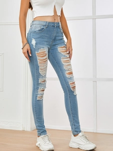 Detail of high waist light blue skinny jeans with distressed ripped knees and elastic fabric