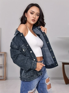 Dettaglio della giacca di jeans grigio scuro con bottoni in metallo e jeans strappati