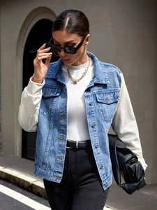 Detail of light blue denim vest jacket with white ribbed long sleeves and metal buttons