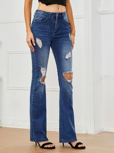 Detail of high-waist dark blue flared jeans with distressed knee holes and ripped details