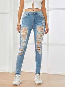 Detail shot of distressed high-waisted light blue skinny jeans with ripped denim texture