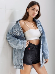 Detail of light blue denim jacket, white camisole top, and black floral shorts