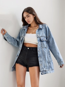Detail of light blue washed denim jacket featuring distressed ripped hem and oversized fit