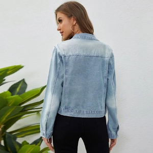 Back view of a cropped light blue washed denim jacket with vintage distressed details