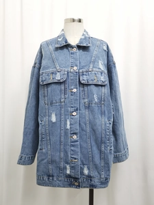 Detailed close-up of oversized blue denim jacket with distressed ripped holes and buttons