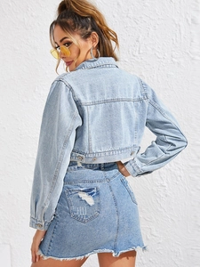 Detail view of light blue denim jacket back panel with frayed hem denim skirt