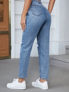 Detail of high-waisted light blue washed denim jeans with distressed knee and back pockets