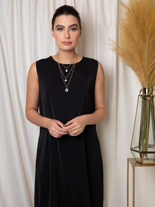 Détail d'un collier doré multi-rangs avec breloques sur une robe noire sans manches
