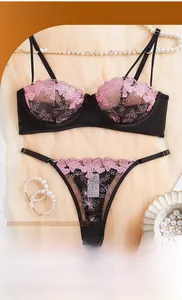 Detail of black mesh bra set with pink flower embroidery on elegant silk background
