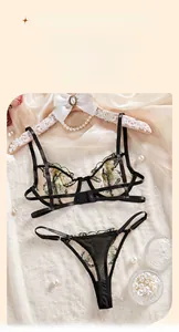 Detail of black strappy lingerie set featuring intricate green butterfly embroidery and bows