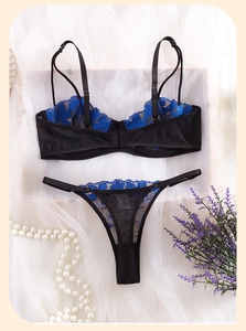 Détail de broderies florales bleues sur l'ensemble de lingerie en maille noire