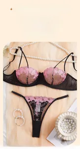 Detailed flat lay of pink lace lingerie set with black mesh and elegant pearl accents