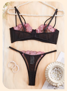 Detailed flat lay of pink floral embroidery and black mesh lace bra set with pearls