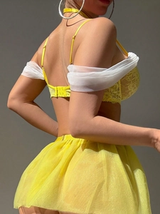Detailed texture of vibrant yellow lace bra and sheer mesh skirt on model side view