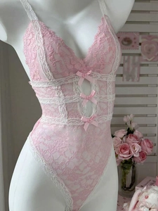 Detail eines rosa Body aus Blumen-Spitze mit weißem Besatz und kleinen Seidenschleifen
