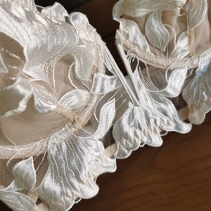 Detailed macro view of delicate leaf embroidery and sheer lace on this luxury bra