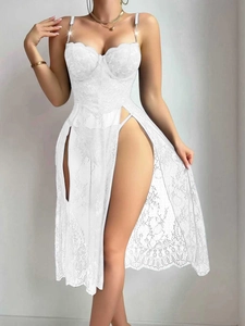 Dettaglio di camicia da notte in pizzo bianco con spacchi alti e spalline di strass