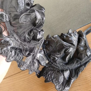 Detail of black lace bra featuring intricate 3D floral embroidery and mesh texture
