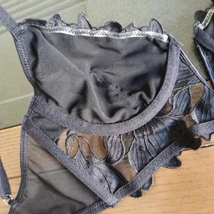 Detail of black lace bra cup showing floral embroidery mesh lining and anti-slip silicone strips