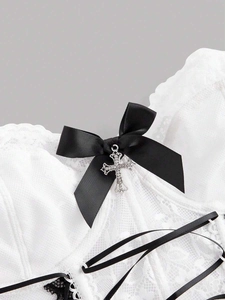 Macro detail of white floral lace corset with black bow and silver cross pendant