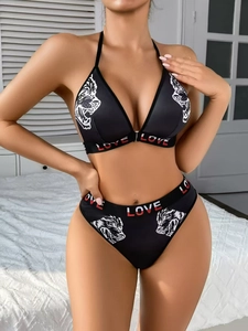 Détail d'un ensemble bikini noir avec imprimé loup et bandes élastiques lettrées LOVE