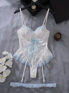 Détail d'un body en dentelle blanche avec bordure florale bleue et porte-jarretelles