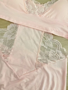 Close-up of light pink modal fabric with delicate white floral lace patchwork detail