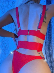 Dettaglio di lingerie rossa con spalline a catena in metallo e design incrociato