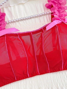Detail of red mesh corset top featuring pink satin bows and 3D floral accents