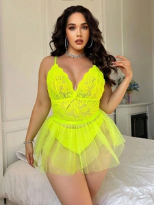 Detail of neon yellow floral lace lingerie with tiered mesh skirt on a model in a bedroom
