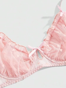 Detail of pink lace bra with mesh heart pattern, ruffled edges and a satin bow