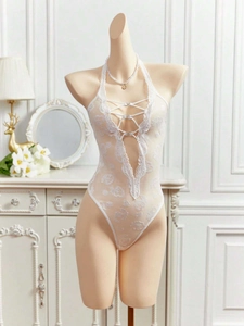 Close-up of white lace bodysuit featuring deep V-neckline and rhinestone cross-tie details