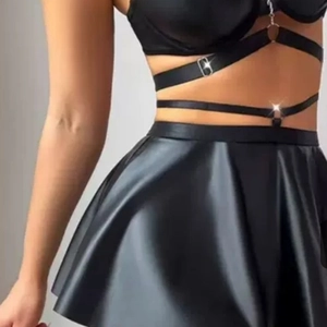 Sexy zwarte kunstleren set voor dames met metalen kettingen en een geplooide minirok