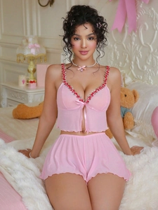 Close-up of pink mesh sleepwear with floral embroidery and a bow tie detail