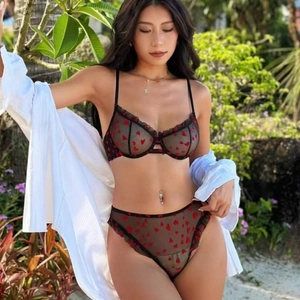 Set di lingerie nera trasparente con cuori rossi e pizzo in un ambiente esterno naturale