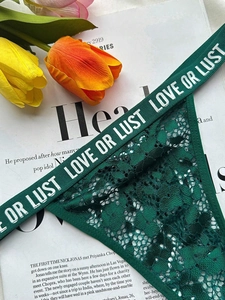 Détail d'une culotte en dentelle vert foncé avec lettrage LOVE OR LUST à la taille