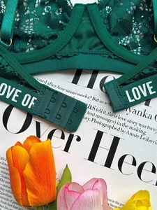 Détail de lingerie en dentelle vert foncé avec bretelles LOVE et fermeture à agrafes