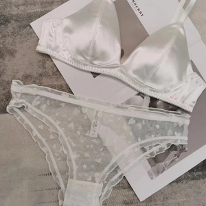 Detailed view of white satin bra and sheer mesh heart-print panties on a magazine