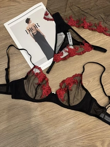 Détail d'un ensemble de lingerie en dentelle noire avec broderie florale rouge