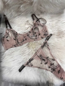 Détail d'un ensemble de lingerie en tulle brodé avec étiquette taille M sur tapis doux