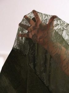 Close-up of olive green floral lace with rose patterns and dark green velvet texture