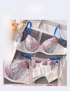 Détail de broderie florale sur soutien-gorge en dentelle blanche à bretelles bleues