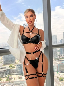 Détail d'un ensemble de lingerie en similicuir noir avec chaînes dorées et anneaux