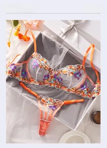 Detailed embroidery view of an orange mesh lingerie set within a premium gift box