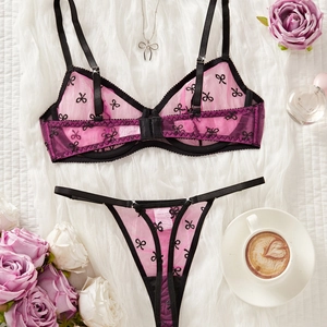 Pink mesh lingerie set with butterfly embroidery and black satin straps on white fabric